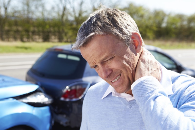 Man in accident clutching his neck due to neck pain and whiplash